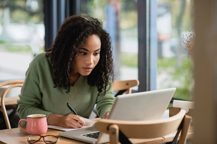 A professional worker engaged in her work while writing down her analysis. 